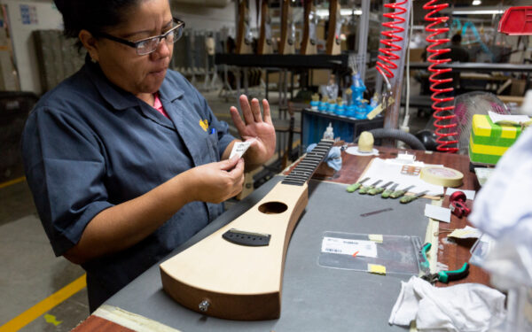 Una mujer pegando la etiqueta de la guitarra acústica Martin Backpacker.