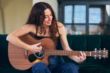 Una mujer tocando la guitarra acústica GPC-X2E Ziricote de la serie x de Martin actualizada