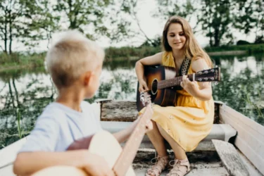 Niño aprendiendo a tocar la guitarra acústica en clase de música