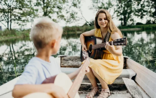 Niño aprendiendo a tocar la guitarra acústica en clase de música