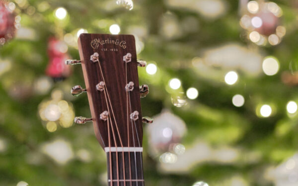 Cabeza de guitarra Martin con luces navideñas de fondo, un regalo perfecto para guitarristas en Navidad.