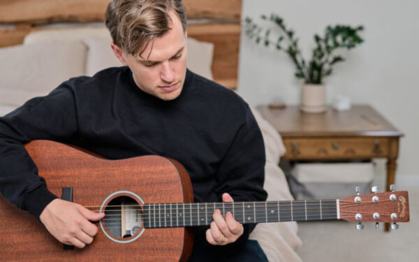 Persona tocando una guitarra acústica Martin tipo Dreadnought, ideal para acompañamientos, rasgueos y estilos como pop, rock y country.