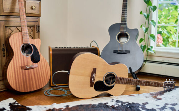 Tres guitarras acústicas Martin de distintos tamaños y diseños colocadas junto a un amplificador.